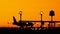 Silhouette of airplanes at the airport at sunny orange and purple sunset. Plane taxiing on the runway preparing for journey.