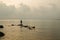 Silhouette alone fisherman stands on rock at sea shore for fish hunt