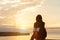 Silhouette alone young woman relax siting on riverside ocean and watching sunset and cloud sky with akashi kaikyo bridge.