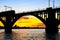 Silhouette of arched railway bridge and a train on the Dnieper river at beautiful sunset. Dnipropetrovsk