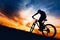 Silhouette of athlete riding mountain bike on hills at sunset