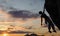 Silhouette of athletic woman climbing steep rock wall