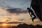 Silhouette of athletic woman climbing steep rock wall