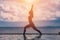 silhouette Athletic woman practice yoga Warrior one pose to meditation summer vacation on pier with sunset sea beach