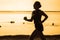 Silhouette of attractive and athletic Asian Indonesian woman running on the beach doing morning jogging workout in professional