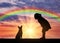 Silhouette of a baby girl and her dog on a background of a sea sunset and a rainbow