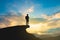 Silhouette of backpacker on mountain top over sky and sun light background.