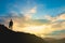 Silhouette of backpacker on mountain top over sky and sun light background.