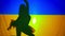 Silhouette of ballerina spinning dancing at background of Ukrainian flag with backlit. Slim unrecognizable woman in tutu