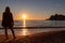 Silhouette of barefoot woman on sand beach with scenic view on idyllic island Sveti Stefan, Budva Riviera, Montenegro
