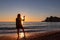 Silhouette of barefoot woman on sand beach with scenic view on idyllic island Sveti Stefan, Budva Riviera, Montenegro
