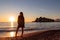 Silhouette of barefoot woman on sand beach with scenic view on idyllic island Sveti Stefan, Budva Riviera, Montenegro