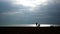 Silhouette beach people and a glowing sea.