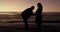 Silhouette, beach and pregnant couple with man rubbing expecting woman stomach or belly at sea in sunset. Baby