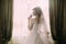 Silhouette of beautiful bride in traditional white wedding dress, stood by window.