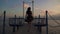 Silhouette of a beautiful girl in a light dress at sunset. A girl is walking a pier on the sea