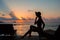 Silhouette of a beautiful slender girl on a sunset background and sun loungers on the ocean shore. Woman watch skyline