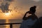 Silhouette of a beautiful woman contemplating sunrise from a balcony over the sea