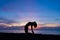 Silhouette of a beautiful woman practicing yoga asana on the beach with sunrise on twilight blue vibrant sky