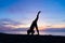 Silhouette of a beautiful woman practicing yoga asana on the beach with sunrise on twilight blue vibrant sky