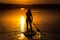 Silhouette of beautiful young girl on SUP in the scenic yellow sunset on lake Velke Darko, Zdar nad Sazovou, Czech republic