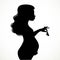 Silhouette of a beautiful young pregnant woman holds in the fingers of a small baby booties