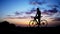 Silhouette of bicycle rider on a rock at sunset