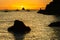 Silhouette of big black stone and sailing boat and tropical island on sunset Philippines