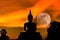 Silhouette big buddha statue on sunset with full moon background