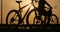 A silhouette of a bike at sunset. The sun shines through the bicycle frame