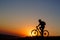 Silhouette of a bike tourist on mountain peak.