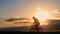 Silhouette biker lovely family on the meadow at sunset time. Silhouette of mother and baby biking at sunset. Lifestyle