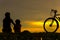 Silhouette biker lovely family at sunset over the ocean. Mom and daughter bicycling at the beach.