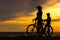 Silhouette biker lovely family at sunset over the ocean. Mom and daughter bicycling at the beach