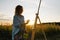 Silhouette of a blonde girl artist. Lady paints a painting on the canvas with the help of paints. A wooden easel keeps