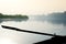 Silhouette of boat oar coming out of water with a foggy river in the background