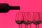 Silhouette of a bottle of wine that fills glasses on a pink background