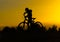 Silhouette of a boy on a bicycle at sunset