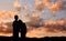 Silhouette of boy and girl stand hand in hand to watch the sunset
