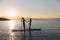 Silhouette of boy and girl on sup surf pull hands together at the ocean. Concept lifestyle, sport, love