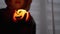 Silhouette of Boy in Hood. Hand Holds a Burning Pumpkin Candle in a Dark Room