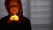 Silhouette of Boy in Hood. Hand Holds a Burning Pumpkin Candle in a Dark Room