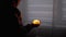 Silhouette of Boy in Hood. Hand Holds a Burning Pumpkin Candle in a Dark Room