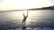 Silhouette of boy jumping from pier at sunset on the sea