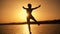 Silhouette of boy jumping from pier at sunset on the sea