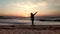 Silhouette of a boy throws sand up on the seashore in the evening at sunset,