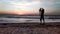 Silhouette of a boy throws sand up on the seashore in the evening at sunset,