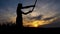 Silhouette of a boy training with a samurai sword at sunset.