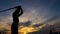 Silhouette of a boy training with a samurai sword at sunset.