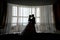 Silhouette bride and groom kissing in front of narrow window